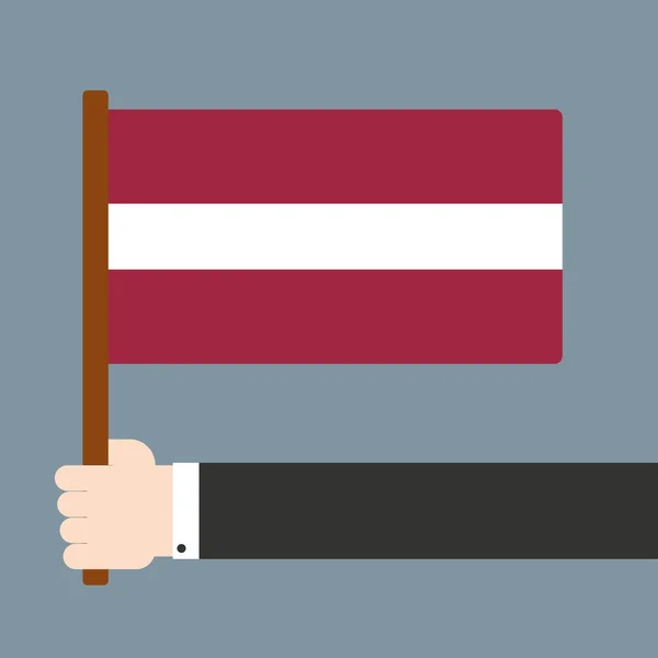 Mão segurando bandeira Letónia — Fotografia de Stock