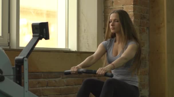 Lento movimento jovem atleta mulher está fazendo alguns exercícios esportivos na máquina de remo — Vídeo de Stock