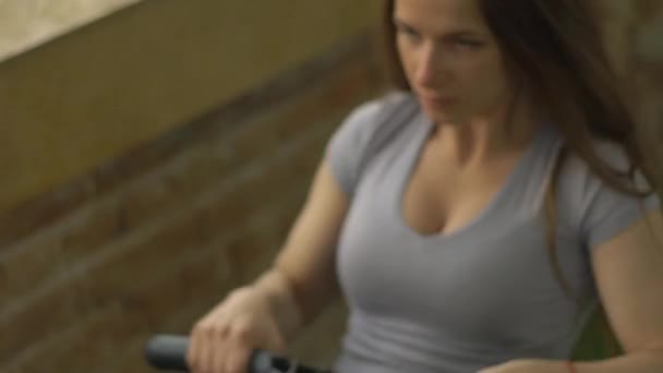 Nő dolgozik az edzőteremben evezőgép — Stock videók