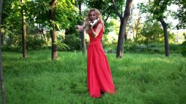 4 k kemancı açık havada keman çalıyor. Artalan yaz yeşil yaprakları.