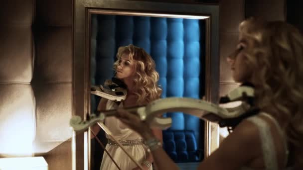 4k Frau schaut in den Spiegel und hält eine Geige — Stockvideo