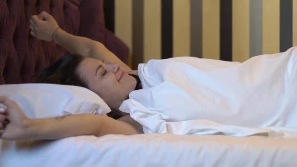 Девочка просыпается в кровати медленным движением — стоковое видео