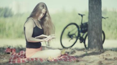 Park ağaç tarafından 4 k genç çekici kadın okuma kitabı