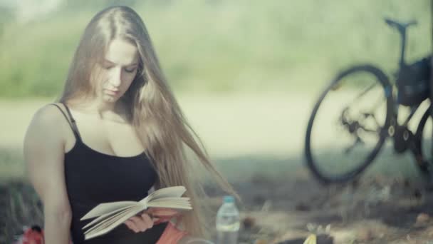 4K jovem mulher atraente lendo um livro no parque — Vídeo de Stock