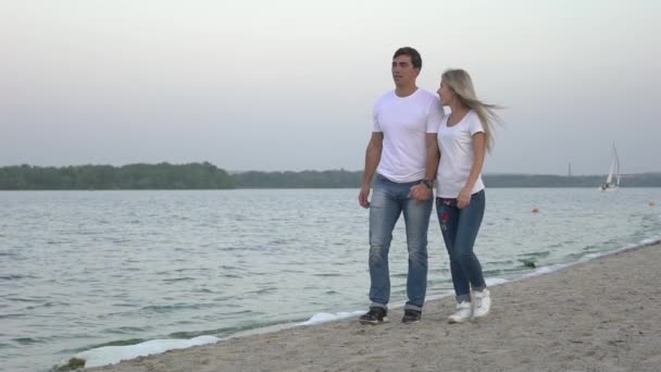 スローモーション ロマンチックなカップルは手を取り合って ビーチの上を歩く — ストック動画
