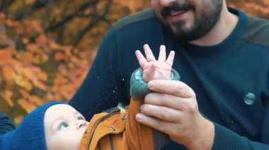 Gerçek zamanlı bir yıl yaşlı erkek bebek sabun köpüğü ile parkta oynarken.