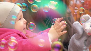 Genç aile bebek Sonbahar Park ile oynarken. Sabun köpüğü ile oynamak