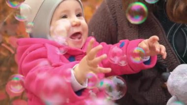 Gülüyor ve sabun köpüğü ile sonbaharda oynarken yavaş mutlu bebek kız