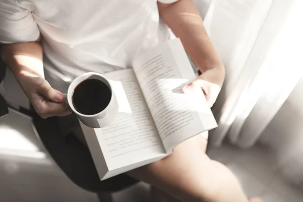 Kitap okuyan ve elinde bir fincan kahve olan genç kadınlar dinlenmenin keyfini çıkarıyorlar, kız kitap okuyor.