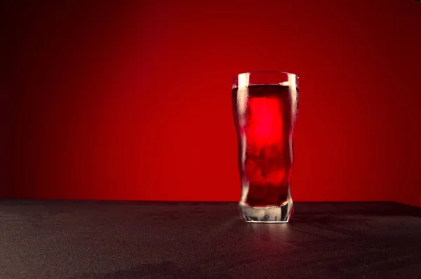 A glass of red drink. Glass of drink on a red background. — Stock Photo, Image