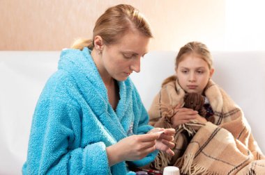 Anne bir çocuğun sıcaklığını ölçer. Çocuk hastalandı..