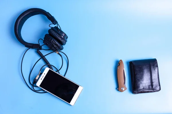 Musical headphones and player. Mobile phone and earphones. Purse and knife.