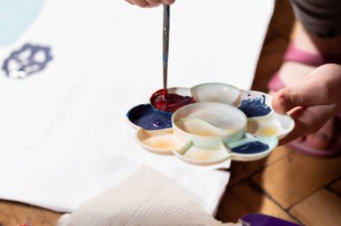 Bir palette boya karışımı. Palette kırmızı ve mavi boya.