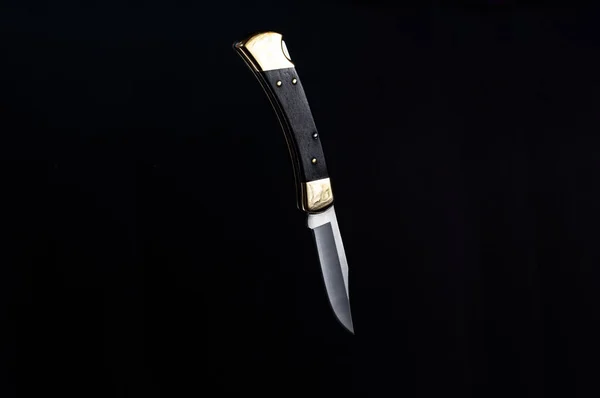 A knife hanging in the air. Knife on a black background.