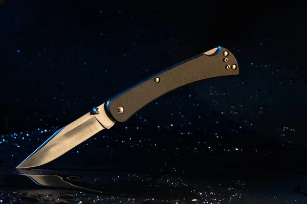 Knife with a black plastic handle on a black background.