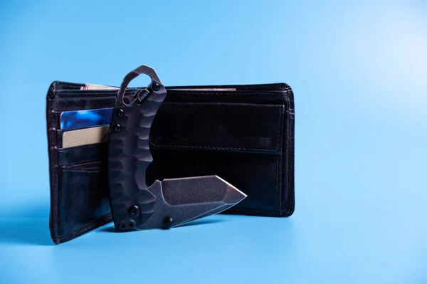 The reverse side of the knife near the wallet. Blue background. — Stockfoto