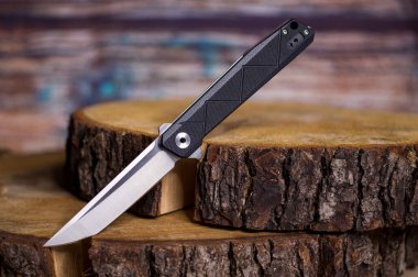 Güzel, dar bir bıçak ve tahta bir kütük. İnce katlanan bıçak. Ahşap arkaplan.