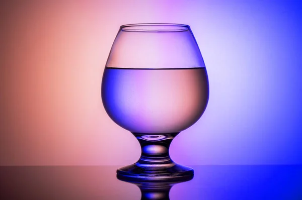 Verre de cognac avec un fond coloré. Beau fond et un verre . — Photo