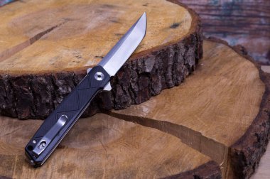 Ahşap dilimler üzerinde katlanan bıçak. Bıçak ve alder ağacı. Şarjörlü cep bıçağı. Çapraz çerçeveli bıçak.