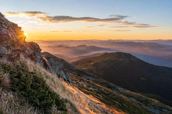 Very beautiful sunrise in the mountains. Early sunbeams in the mountains. Beautiful mountainous terrain. Stones foreground.