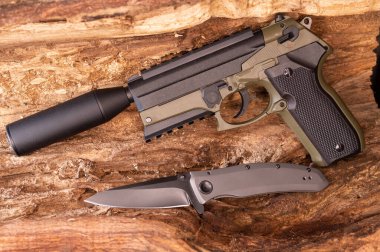 Çukurun ortasında bir bıçak ve silah. Susturuculu bir silah. Üst.