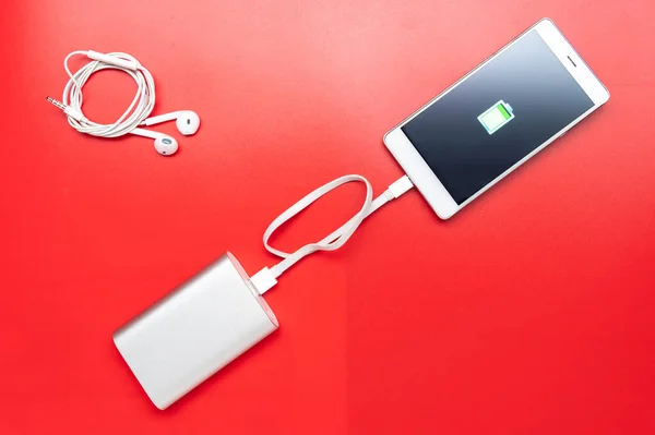 Charge your mobile device and headphones for music. Waiting for a charge of energy. White mobile devices. Flat lay.