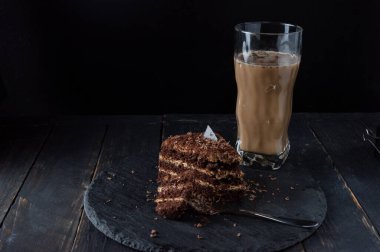 Çikolatalı kek ve latte. Bir dilim pasta ve tatlı çatalı. Şeffaf bardakta Latte..