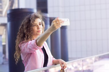 Kıvırcık kız Pembe gömlekli selfie yapıyor