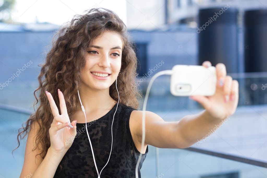 Curly girl holds a video chat with your friends, outdoors