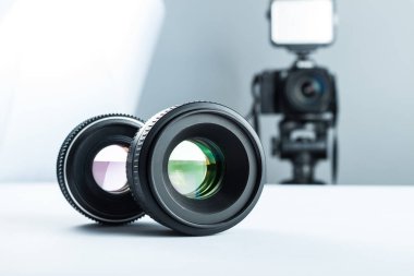 Two lenses on a white table against the background of the camera to light and softbox. clipart