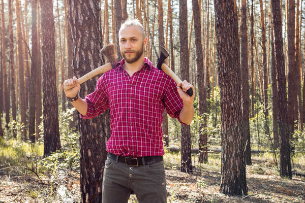 Bearded man with a hatchet in the woods on a background of trees