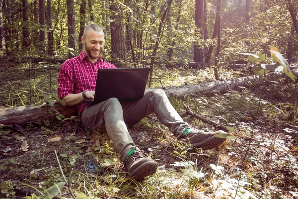 Hipster sentado en el suelo con un ordenador portátil, siempre en línea —  Fotos de Stock