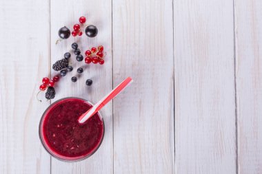 Dut çilek, böğürtlen, kuş üzümü ve cam ahşap masa üzerinde güler yüzlü. Düz kompozisyon