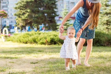 Kız ilk adımları park, annemin elini tutarak yapar.