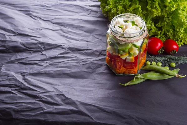 Insalata di verdure fresche con verdure nella pentola su un asse di legno, sfondo strutturato nero. Con spazio per il testo. Cibo sano . — Foto Stock