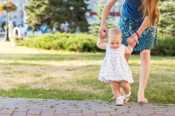 Mamá y su hija aprenden a caminar en el parque . Imagen de stock