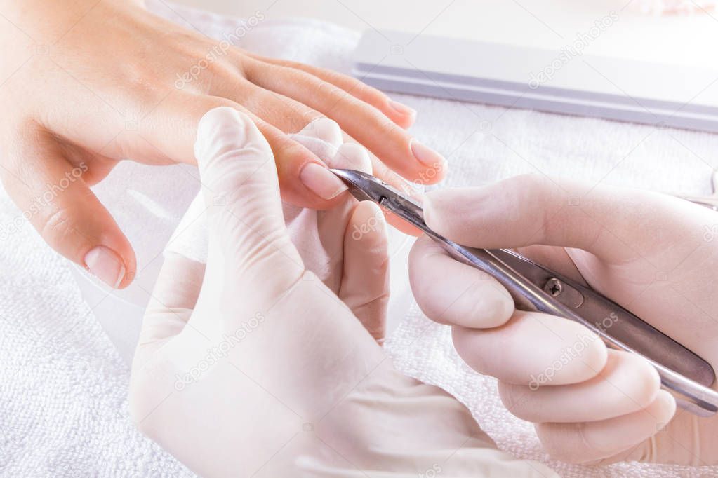 Closeup finger nail care by manicure specialist in beauty salon. Manicure clear cuticle professional nippers for manicure.