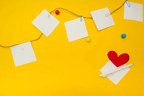 Papel, clipes de papel, coração e corda sobre fundo amarelo, com espaço para texto . — Fotografia de Stock