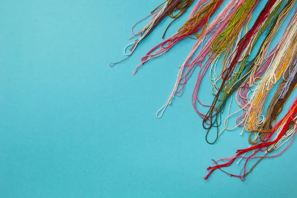 Разноцветная пряжа, используемая для вязания одежды на синем полосатом фоне . — стоковое фото