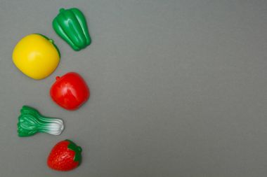 Yapay meyve ve sebzeler üzerinde gri bir arka plan