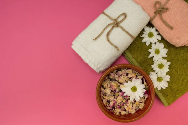 Flowers in the water and towels on pink background — Stock Photo, Image