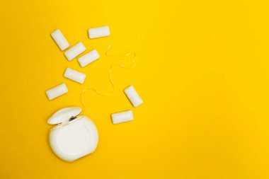 Sarı bir arka plan üzerinde diş ipi ve sakız yastıkları.