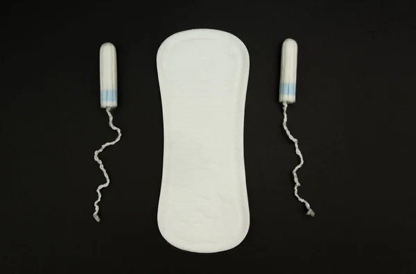 Mujer Sanitary pads and tampons on a black background . —  Fotos de Stock