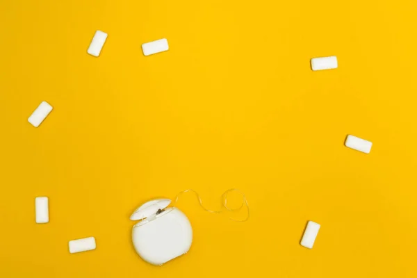 Gomma da masticare e filo interdentale su fondo giallo. Spazio per t — Foto Stock