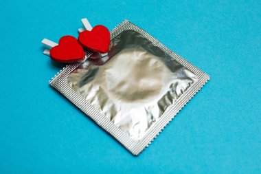 Prezervatif ve mavi bir arka plan üzerinde iki kalp.