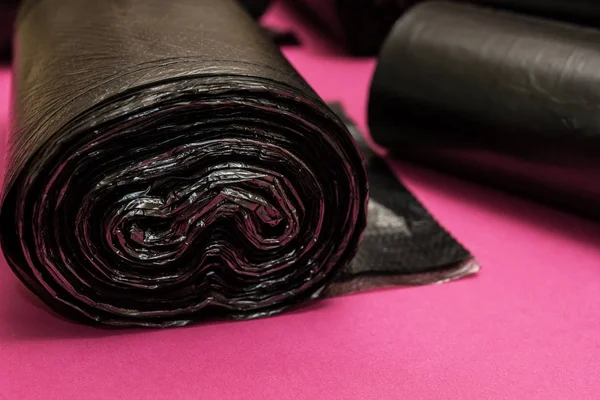 Új fekete szemeteszsákok egy rózsaszín háttér. — Stock Fotó