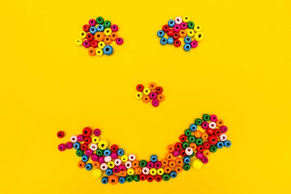 Smiley od wielo--kolorowy okrągły zabawki na żółtym tle. — Zdjęcie stockowe