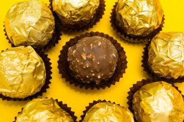 Sarı bir arka plan üzerinde altın bir sarmalayıcı Fındıklı çikolata tatlılar.