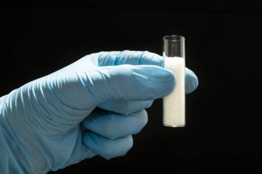 Medikal Ürünler siyah bir zemin üzerine bir doktor elinde bir cam tüp içinde şeker.