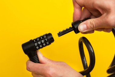 El bir bisiklet şifreli kilit sarı bir arka plan üzerinde bağlanmak.